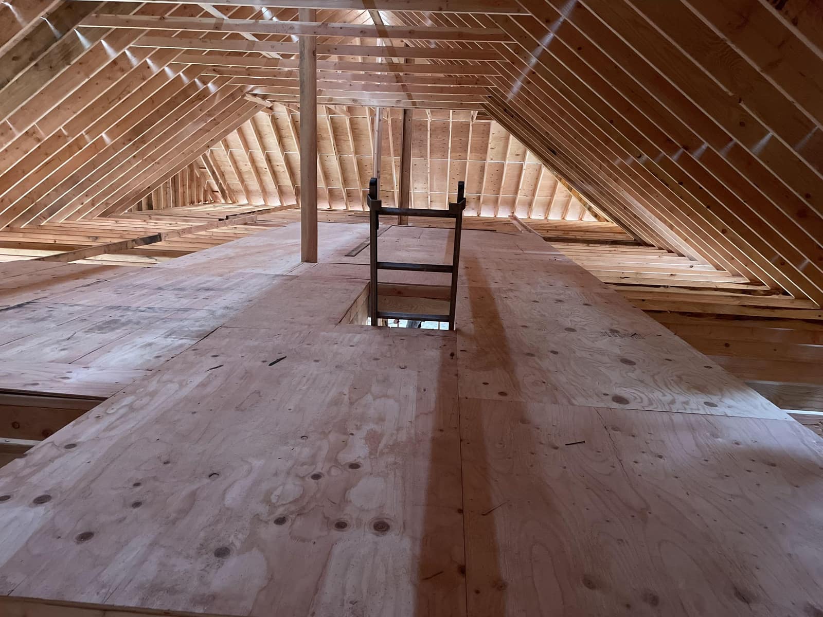 Unfinished attic space with exposed wood rafters, roof framing, plywood flooring, and ladder access, built by Cursi Construction Inc.