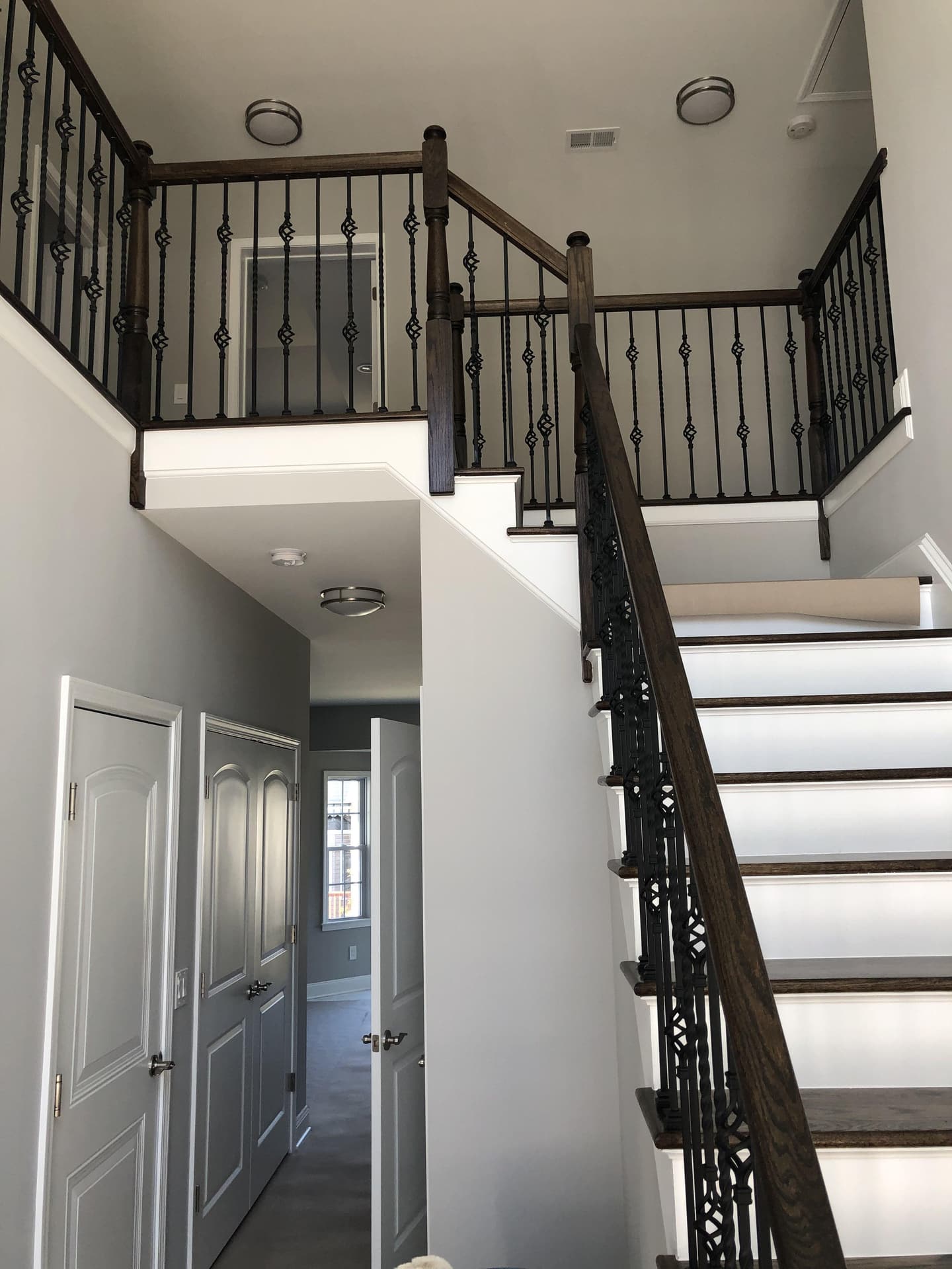 Interior staircase with dark wood railings and ornate black iron balusters in a renovated home, built by Cursi Construction Inc.