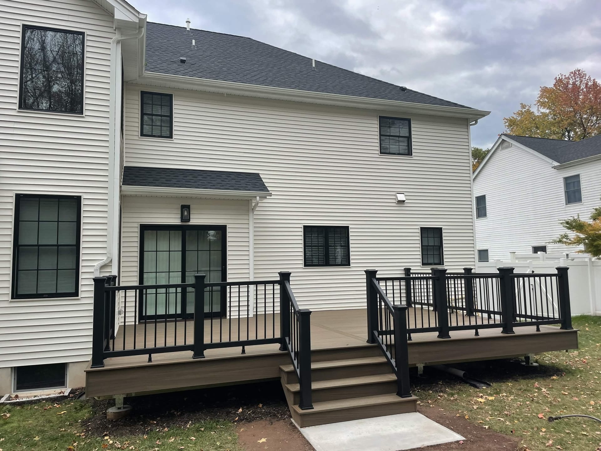 Composite deck with black aluminum railings and stairs on rear of two-story home, built by Cursi Construction Inc.