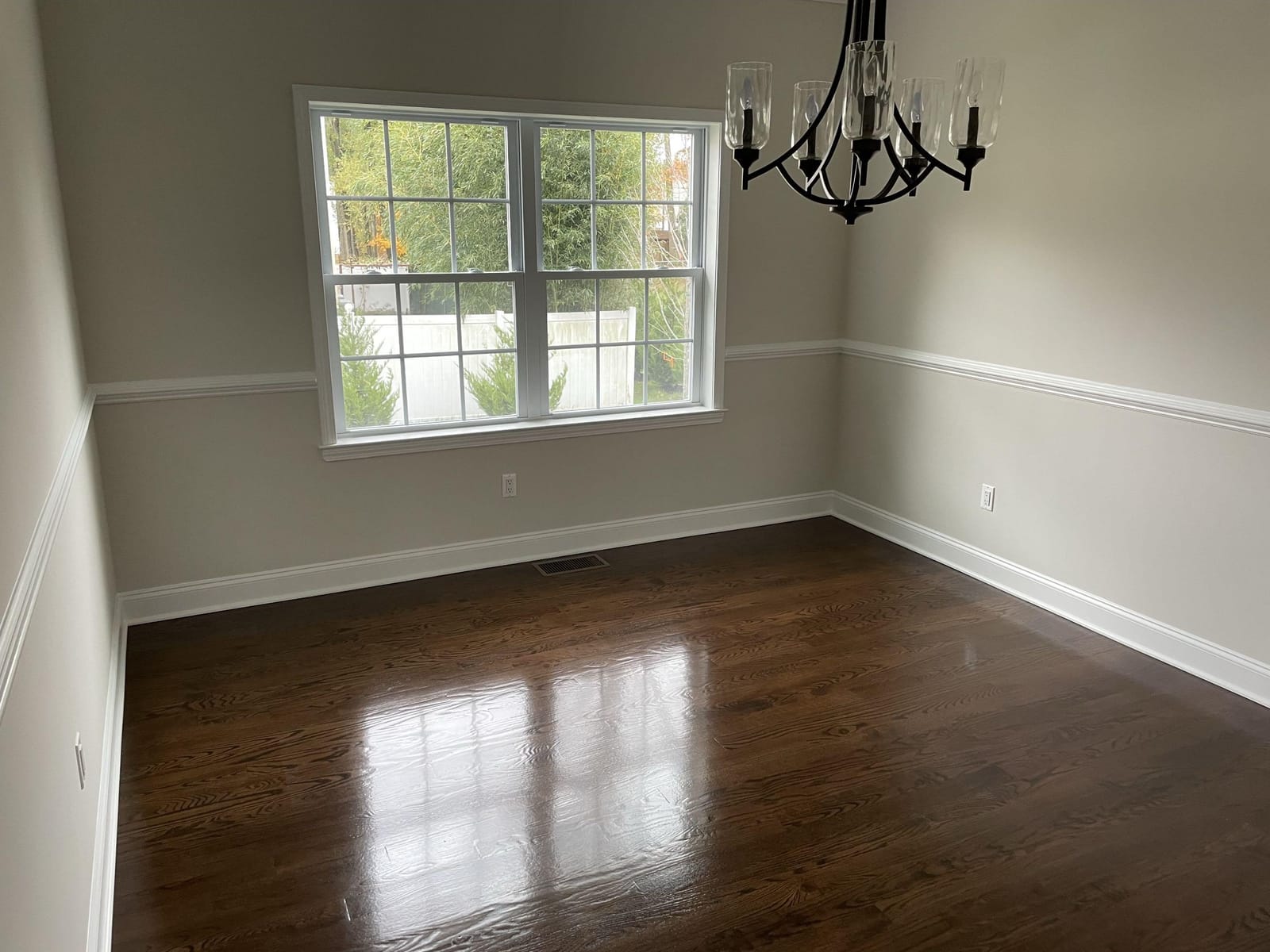 Dining room with large window, white trim, chair rail molding, beige walls, chandelier, and hardwood flooring, built by Cursi Construction Inc.