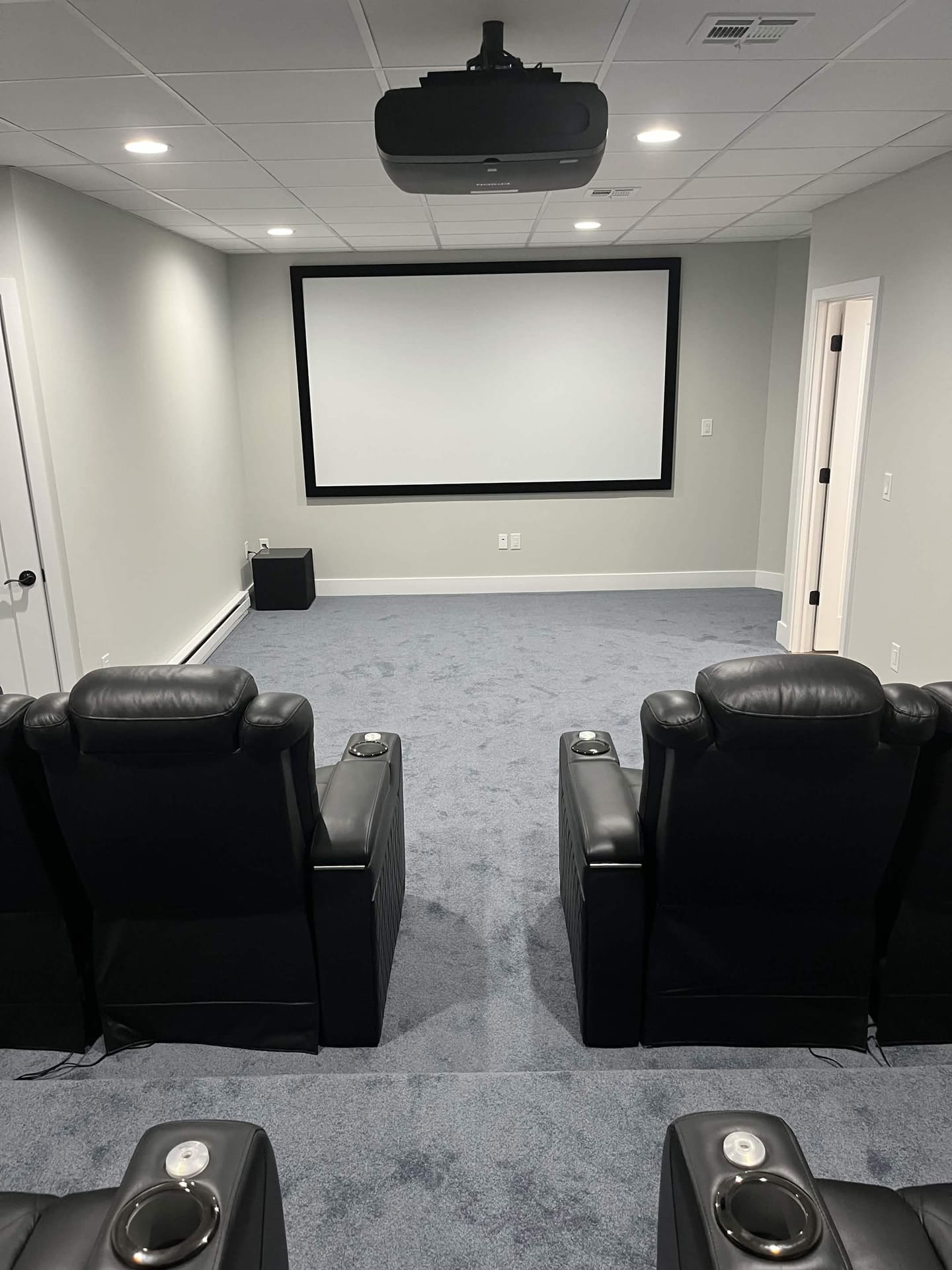Finished basement projector screen and theater seating by Cursi Construction Inc.