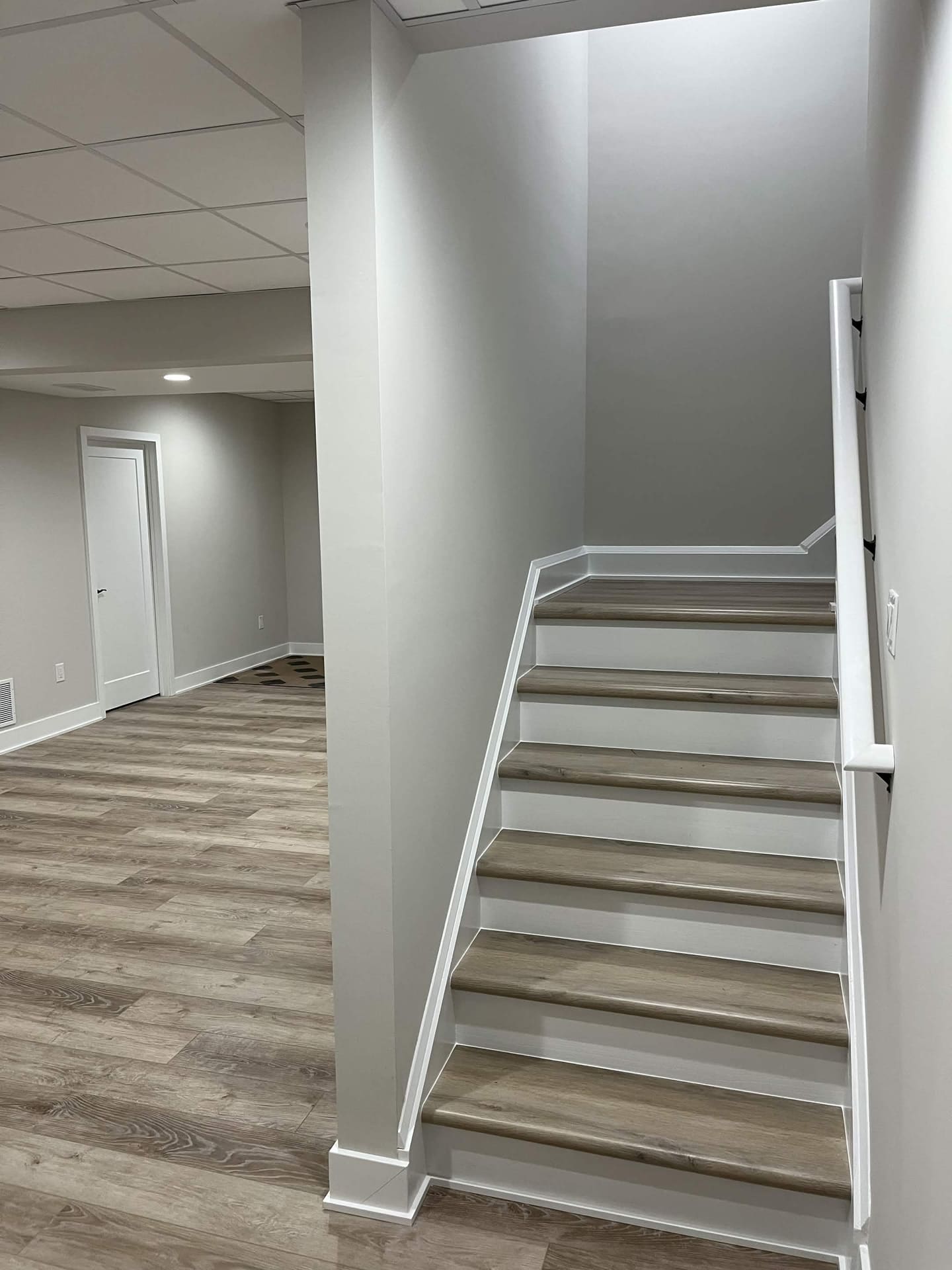 Finished basement staircase with LVP flooring and white trim by Cursi Construction Inc.