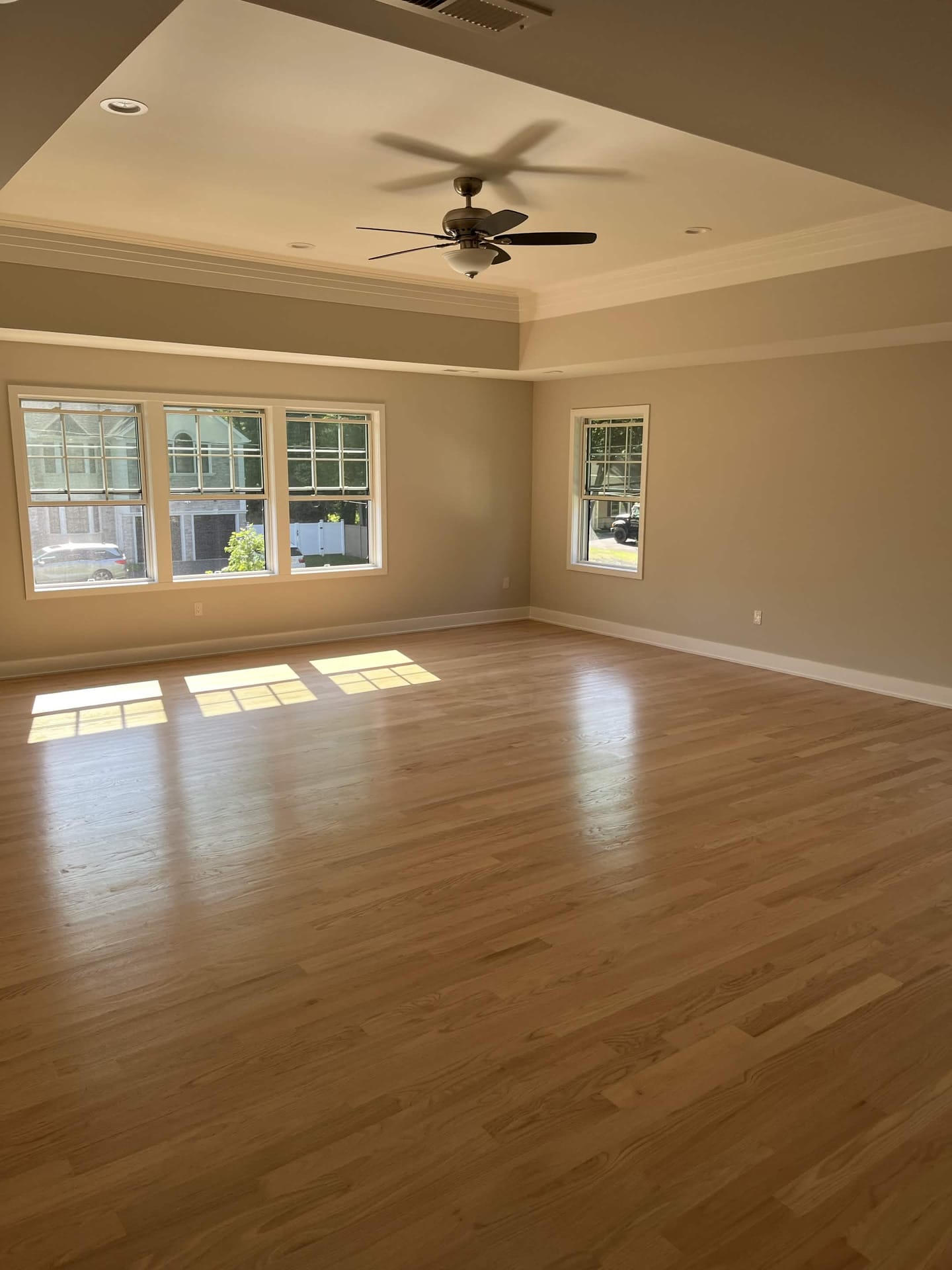 Finished room with hardwood flooring, tray ceiling, crown molding, recessed lighting, and ceiling fan, built by Cursi Construction Inc.