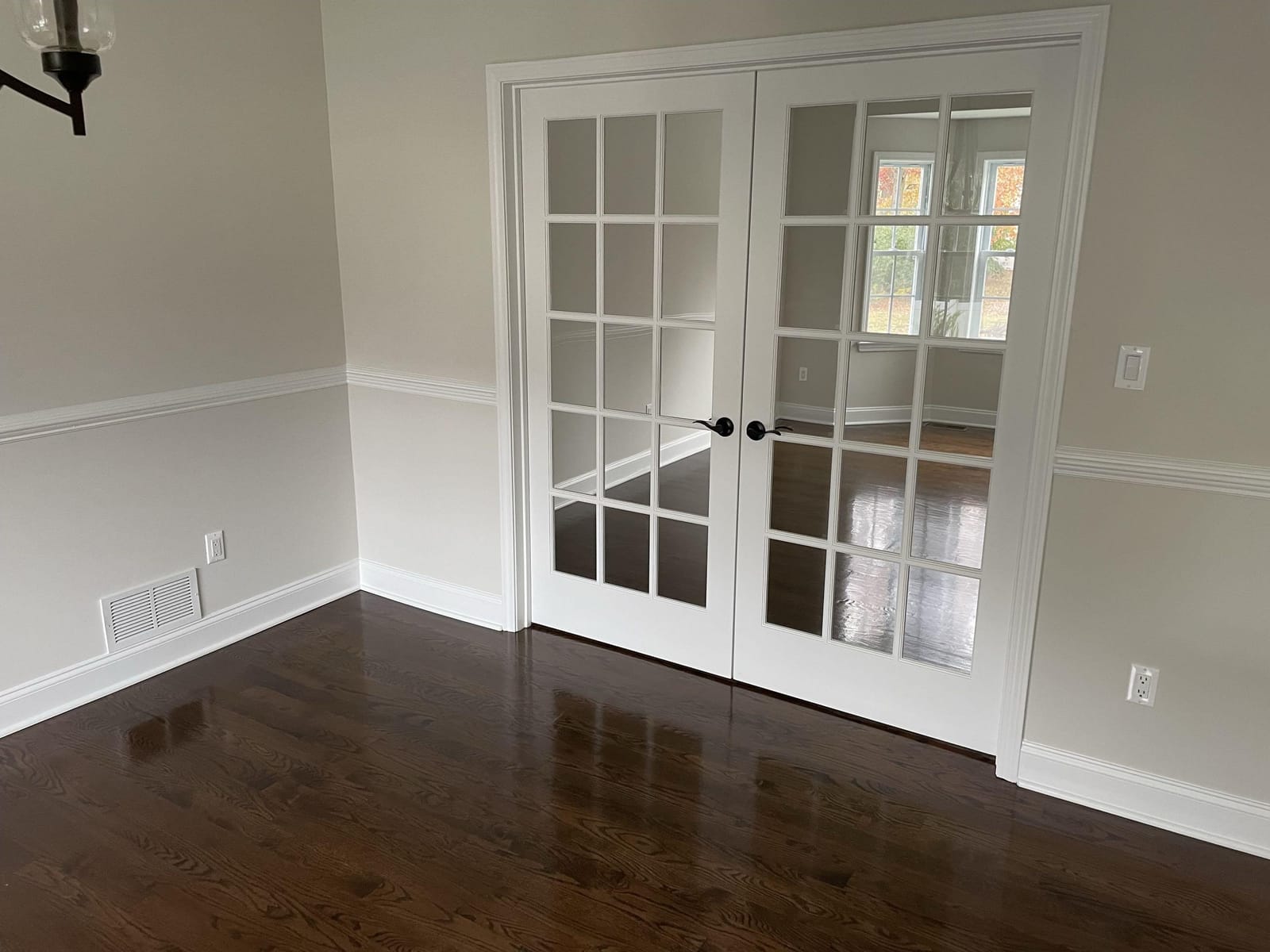 Interior room with white French doors, chair rail molding, gray walls, and dark hardwood floors, built by Cursi Construction Inc.