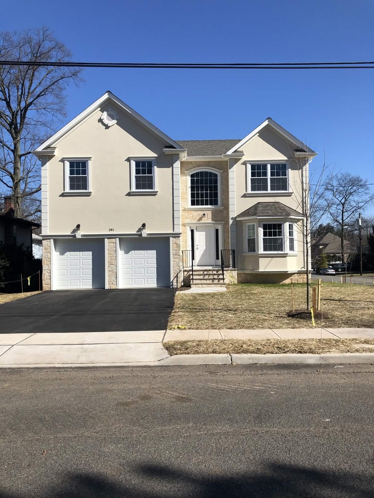 New home construction. Two-story home with stucco and stone accents, bay window, and two-car garage, built by Cursi Construction Inc.