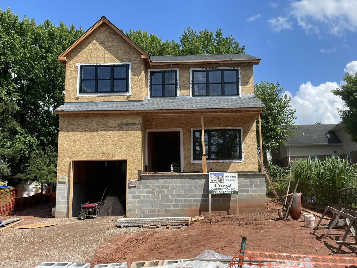 Front view of a new home under construction with block foundation, framed second floor, and garage opening by Cursi Construction Inc.