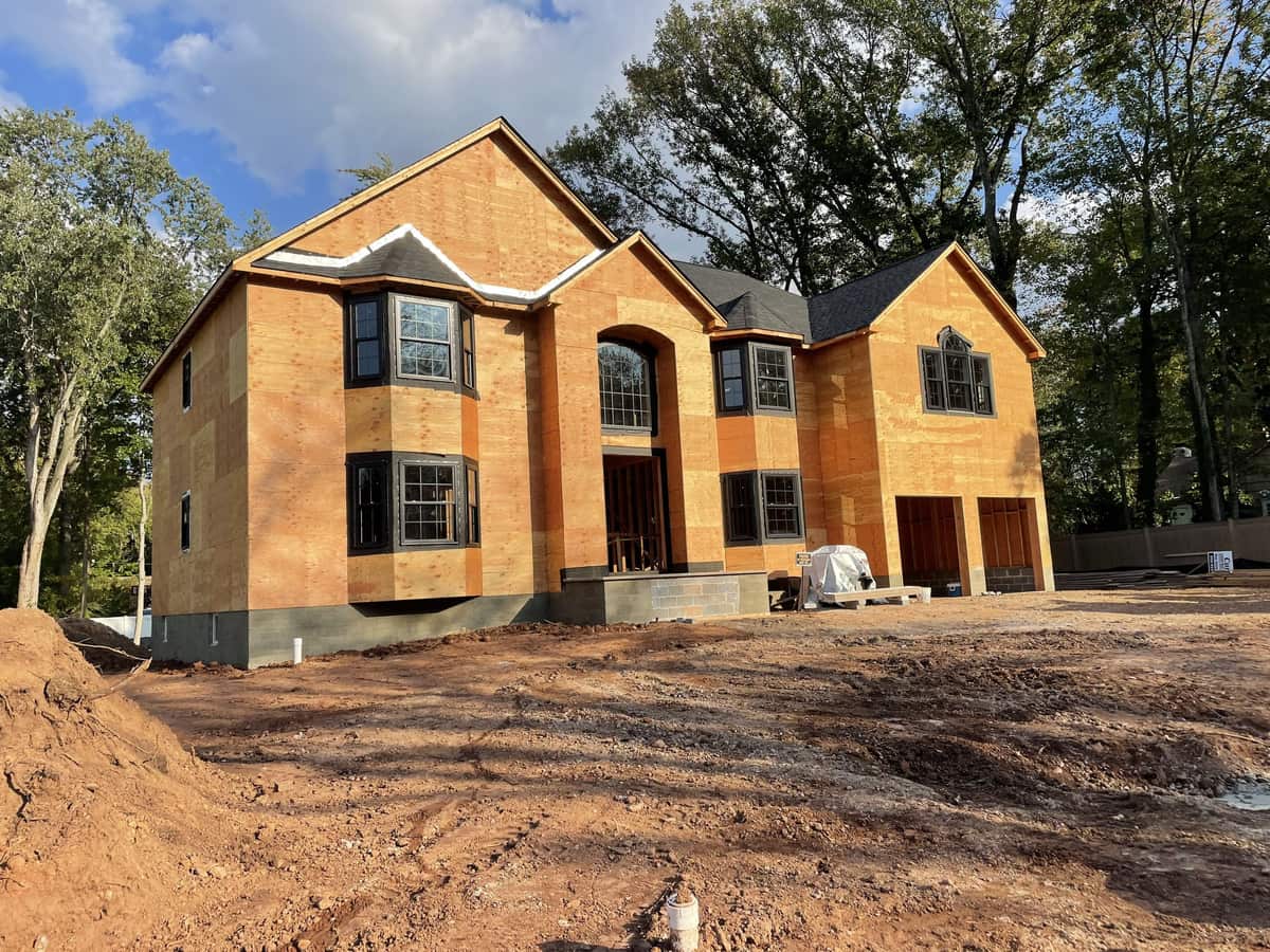 New custom home under construction with roof, sheathing, windows, and front entry framing by Cursi Construction Inc.