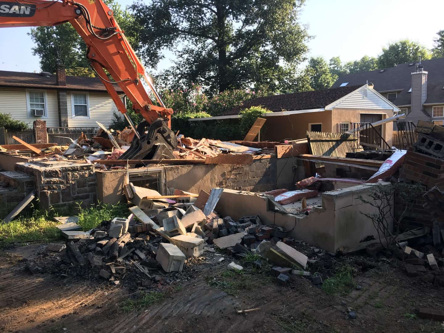 Excavator clearing debris from a demolished residential structure in preparation for new construction, by Cursi Construction Inc.