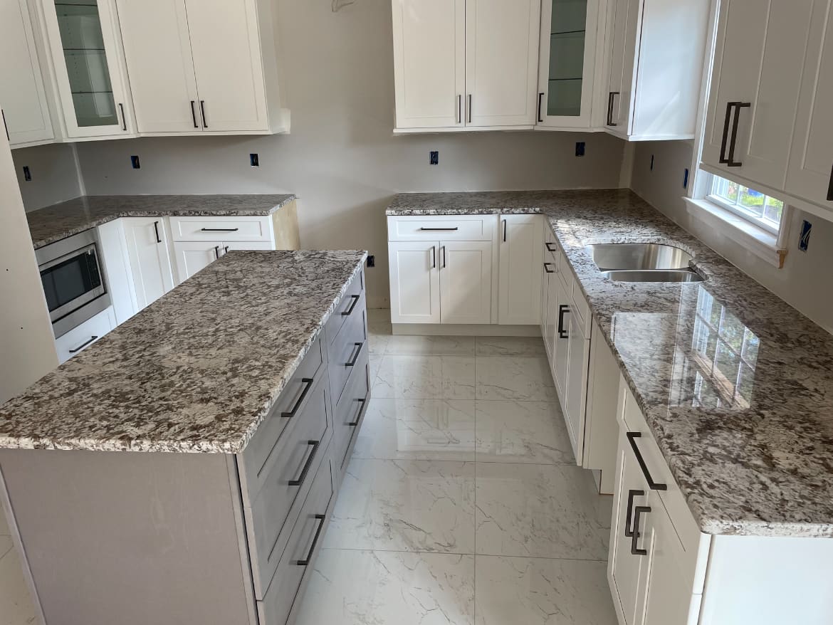 White kitchen renovation with granite countertops, white cabinets, tile backsplash, and marble-look floor tile, built by Cursi Construction Inc.